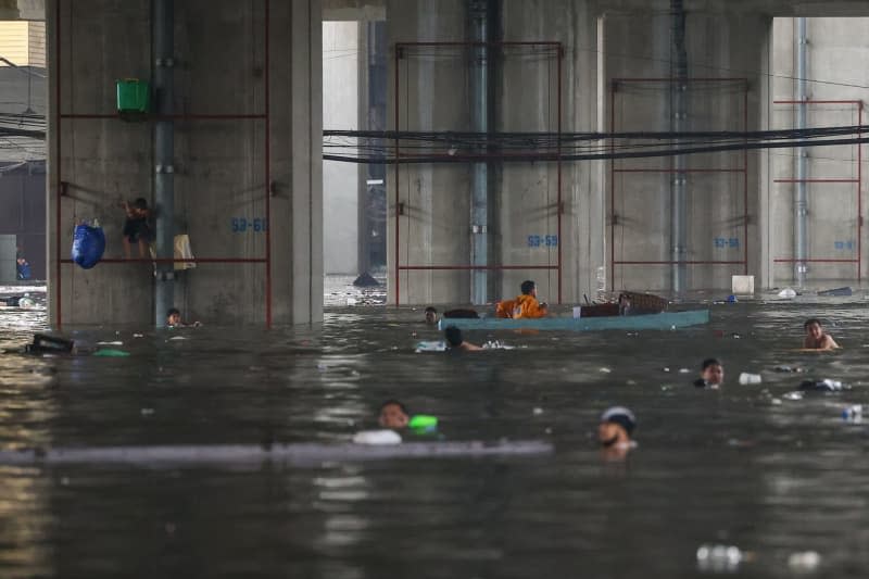 People wade through floodwaters after heavy monsoon rains. The Philippine government has declared a state of emergency in Manila after heavy rains brought by the southwest monsoon and Typhoon Gaemi caused significant flooding in the city and surrounding areas. Basilio Sepe/ZUMA Press Wire/dpa