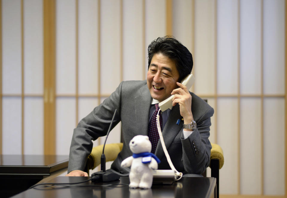 Japanese Prime Minister Shinzo Abe talks to Japan's Yuzuru Hanyu, winner of Sochi Olympics men's figure skating gold medal, on a phone at the prime minister's residence in Tokyo, Saturday, Feb. 15, 2014. Japan celebrated Hanyu's historic win in men's figure skating at the break of dawn Saturday, rejoicing in the country's first-ever gold medal in the Olympic event. (AP Photo/Franck Robichon, Pool)