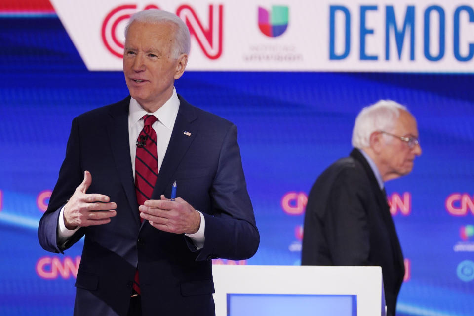 FILE - In this March 15, 2020, file photo Sen. Bernie Sanders, I-Vt., right, and former Vice President Joe Biden, left, return to the stage after a commercial break in a Democratic presidential primary debate at CNN Studios in Washington. White House contenders aren't typically bashful about asking for money. But as the coronavirus pandemic upends life, President Donald Trump and his likely Democratic rival, Biden, suddenly find themselves navigating perilous terrain. (AP Photo/Evan Vucci, File)