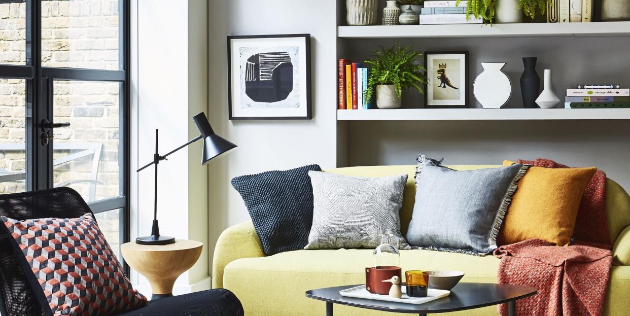 sitting room, yellow sofa white shelf behind with a blue and yellow patterned rug