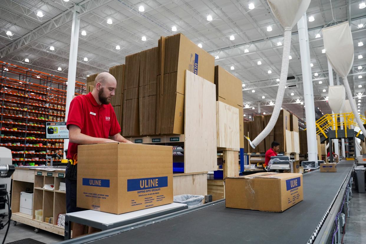 Employees pack boxes for shipping at the Uline warehouse in Naples on Tuesday, April 18, 2023.