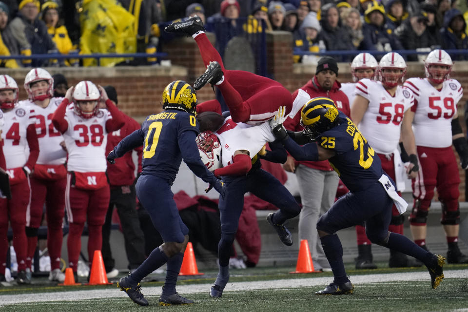 Nebraska wide receiver Alante Brown (4) is upended by Michigan defensive back Mike Sainristil (0) as DJ Turner (5) looks on in the first half of an NCAA college football game in Ann Arbor, Mich., Saturday, Nov. 12, 2022. (AP Photo/Paul Sancya)