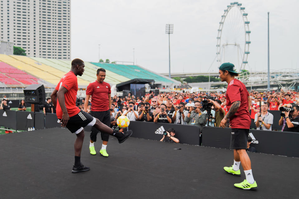 Manchester United's Paul Pogba (left) attempting to juggle a sepak takraw ball as Singapore football great Fandi Ahmad (second from left) watches on in an adidas meet-and-greet fan session at The Float@Marina Bay. (PHOTO: adidas)