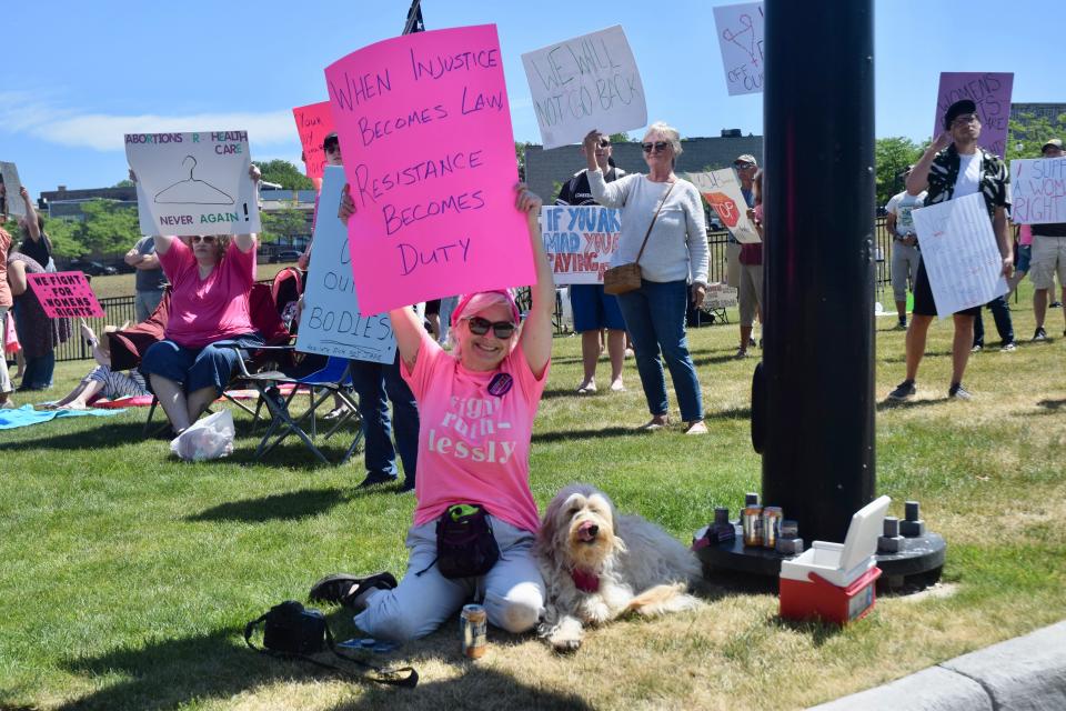 Diane Gildersleeve holds up a sign reading "When injustice becomes law, resistance becomes duty," along US-31, in front of the hole in downtown Petoskey on Sunday, July 3.