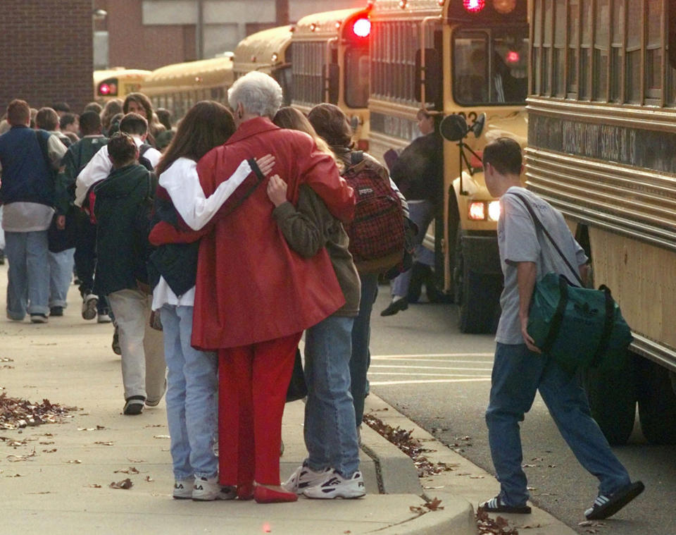 FILE - Students arriving at Heath High School in West Paducah, Ky., embrace an unidentified adult on Tuesday, Dec. 2, 1997, after student Michael Carneal opened fire at the school the day before, leaving three students dead and five wounded. In the quarter century that has passed, school shootings have become a depressingly regular occurrence in the U.S. Carneal's upcoming parole hearing in September 2022, raises questions about the appropriate punishment for children who commit heinous crimes. Even if they can be rehabilitated, many wonder if it is fair to the victims for them to be released. (AP Photo/Mark Humphrey, File)