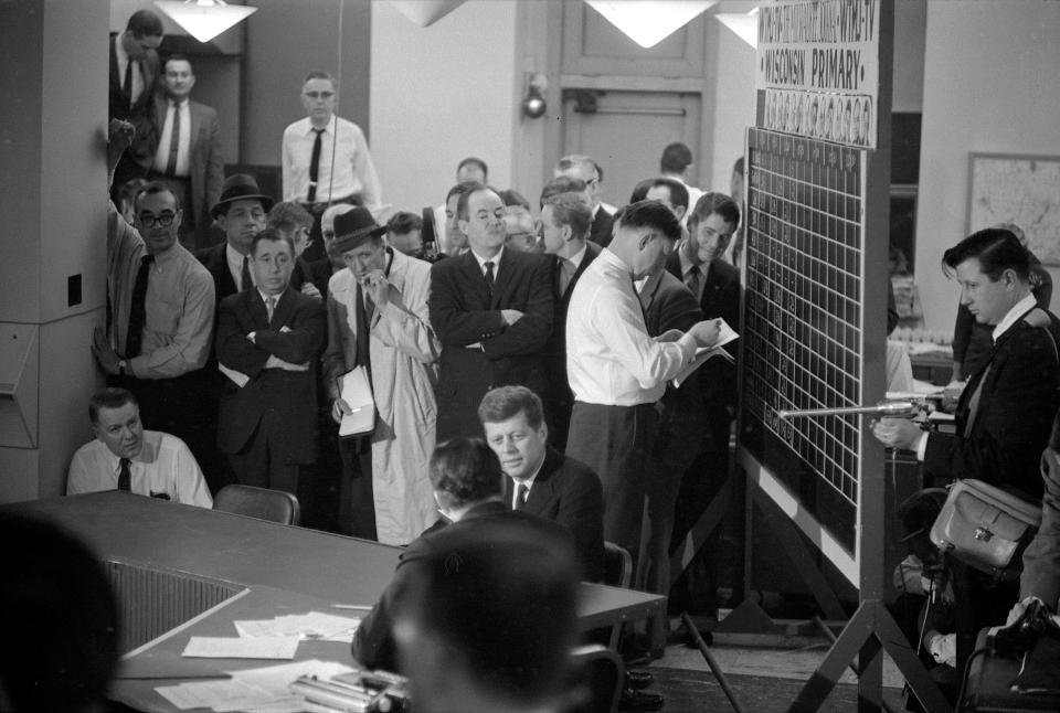 Sen. John F. Kennedy, center, is interviewed by NBC reporter Sander Vanocur in The MIlwaukee Journal newsroom on April 5, 1960, the night of the Wisconsin primary. Kennedy's chief rival, Sen. Hubert Humphrey, is seen standing behind Kennedy with his arms folded. At right, votes are tallied on a chalkboard while a member of the TV crew holds a boom mic to pick up the interview. This photo was published in the April 6, 1960, Milwaukee Journal.