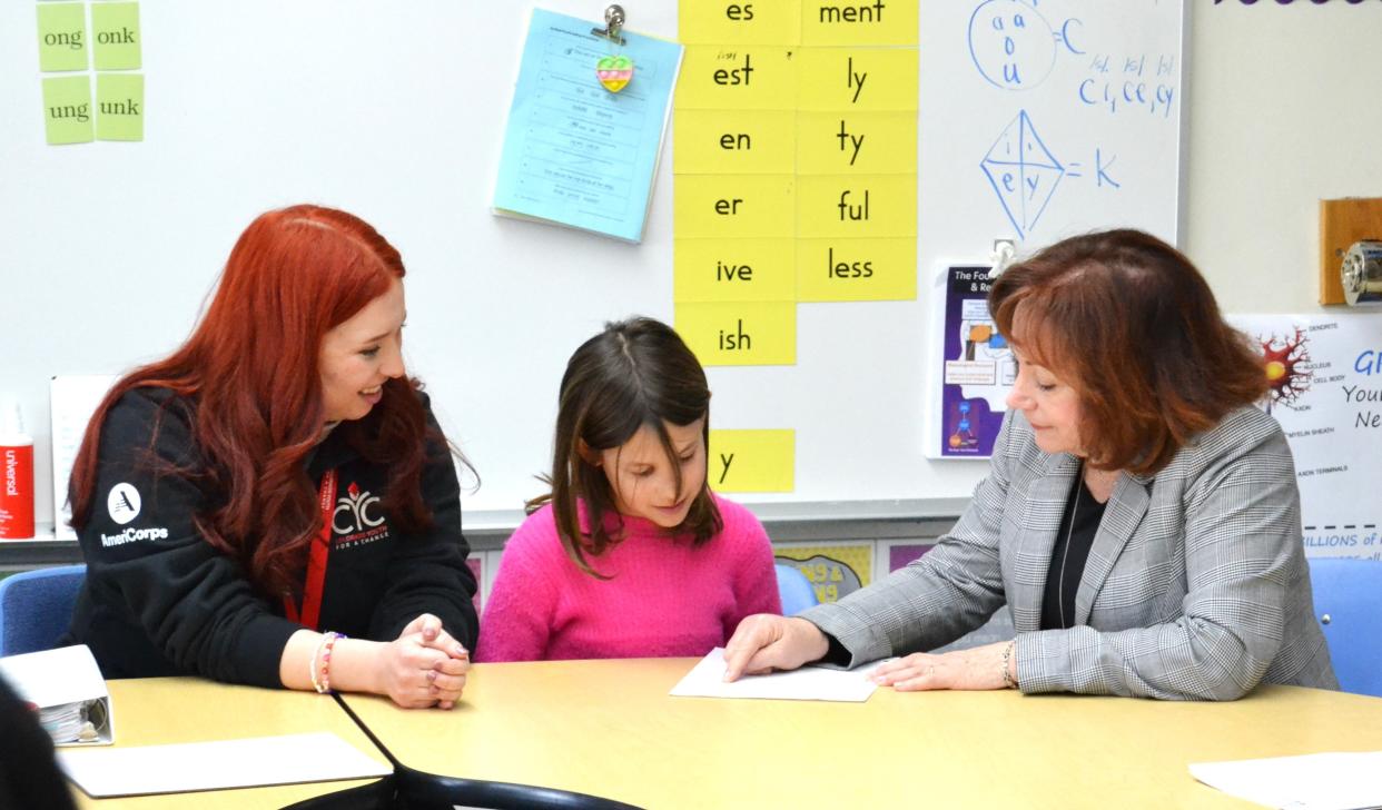 Reading Corps tutor Caroline Iusi, left, looks on as second grader Addison Gunter works with Colorado Lt. Gov. Dianne Primavera in a reading session Wednesday at Coyote Ridge Elementary School in Fort Collins.