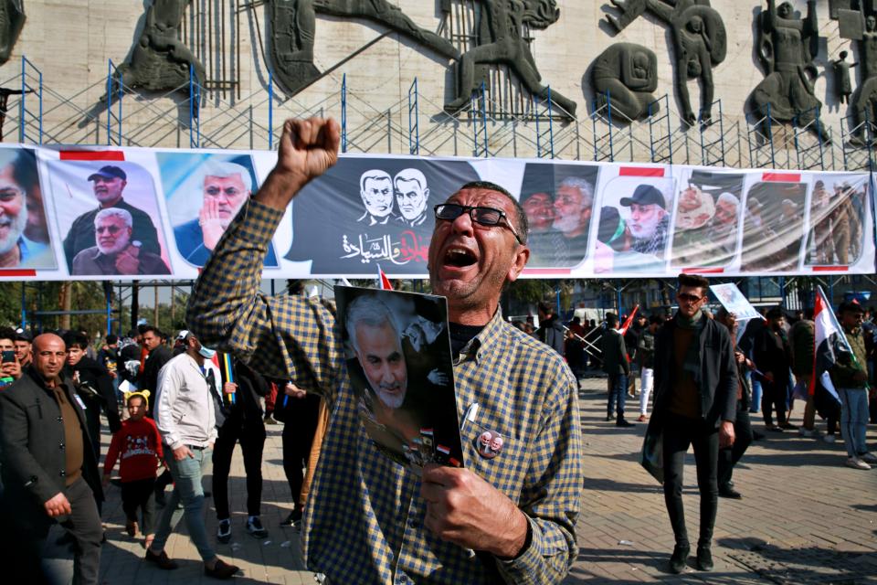 A man chants slogans against the United States while supporters of Popular Mobilization Forces hold posters of Abu Mahdi al-Muhandis, deputy commander of the Popular Mobilization Forces, and General Qassem Soleimani, head of Iran's Quds force during a protest, in Tahrir Square, Iraq, Sunday, Jan. 3, 2021. Thousands of Iraqis converged on a landmark central square in Baghdad on Sunday to commemorate the anniversary of the killing of Soleimanil and al-Muhandis in a U.S. drone strike. (AP Photo/Khalid Mohammed)