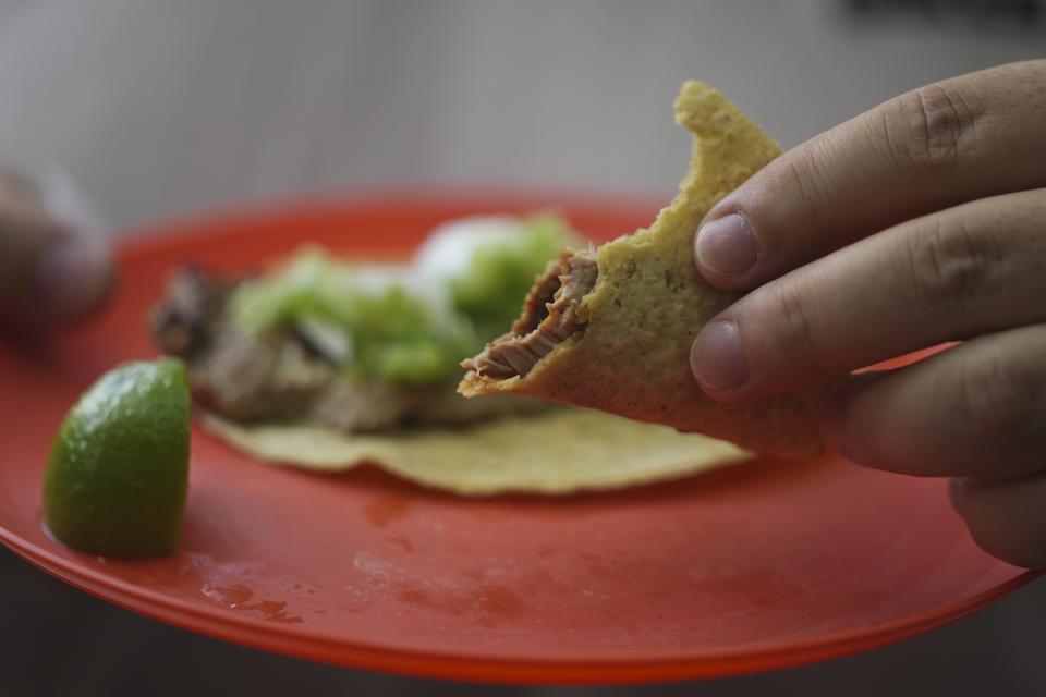 Un cliente con un taco a medio comer en la taquería Tacos El Califa de León en Ciudad de México, el miércoles 15 de mayo de 2024. Tacos El Califa de León es la primera taquería en recibir una estrella Michelin. (AP Foto/Fernando Llano)