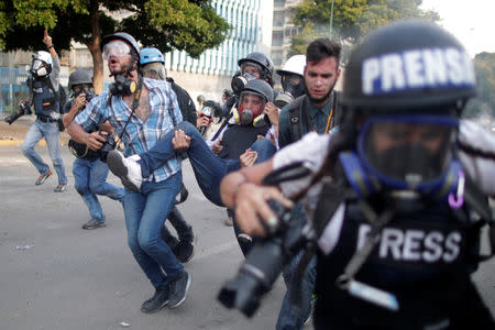 An injured member of the media (C) is carried away during a rally against the government of Venezuela's President Nicolas Maduro and to commemorate May Day in Caracas, Venezuela May 1, 2019. REUTERS//Ueslei Marcelino