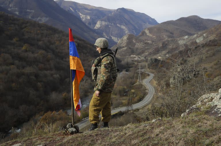 En esta foto del 25 de noviembre de 2020, un soldado de etnia armenia hace guardia junto a la bandera de Nagorno Karabaj en la cima de la colina cerca de Charektar