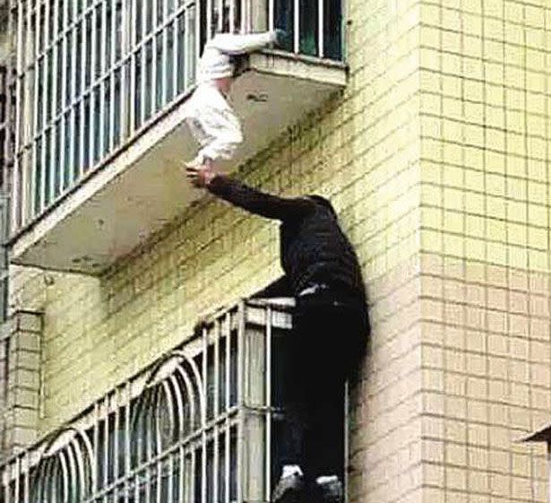 This is the moment a brave Samaritan scaled a building to save an infant found dangling by its neck off a balcony in China. Photo: CCTV