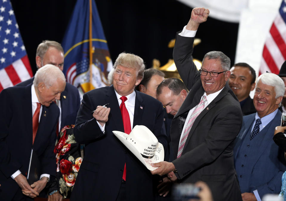 FILE - In this Dec. 4, 2017, file photo, President Donald Trump signs the hat of Bruce Adams, chairman of the San Juan County Commission, after signing a proclamation to shrink the size of Bears Ears and Grand Staircase Escalante national monuments at the Utah State Capitol, in Salt Lake City. Navajo voters could tip the balance of power in their county on Nov. 6. It’s the first general election since a federal judge decided racially gerrymandered districts illegally minimized the voices of native voters who make a slim majority of the population in San Juan County, Utah. It overlaps with the Navajo Nation, where people face huge disparities in health, education and economics. (AP Photo/Rick Bowmer, File)