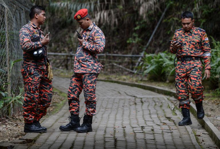 Members of a Malaysian rescue team listen to their radios at the Timpohon gate checkpoint after an earthquake in Kundasang, a town in the district of Ranau on June 6, 2015