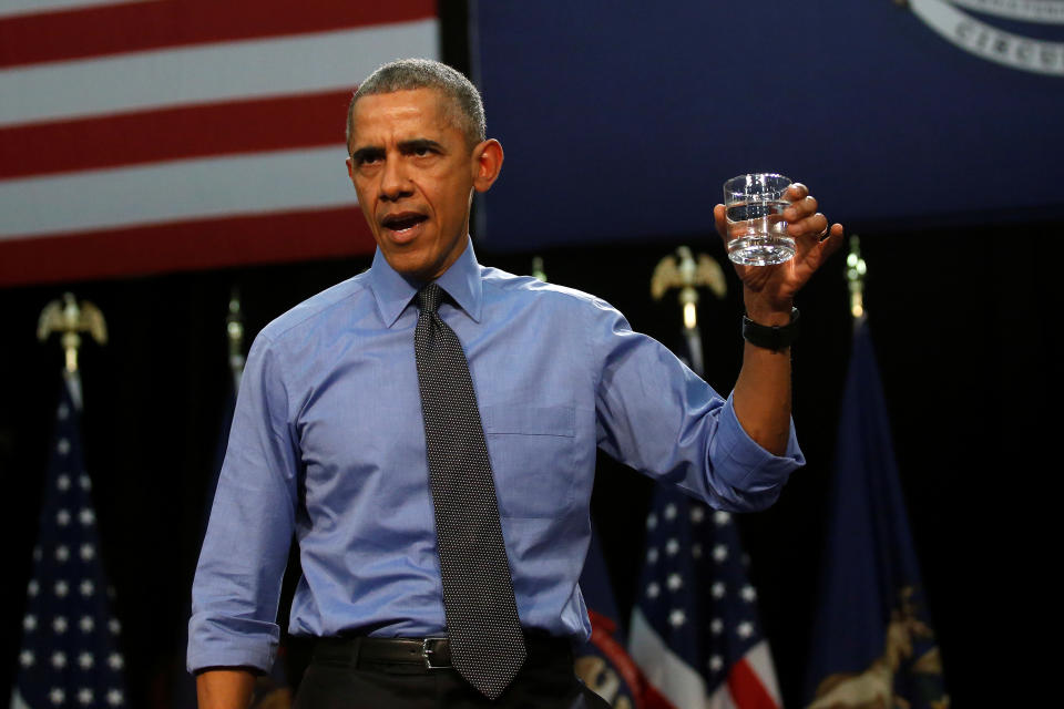 President Barack Obama, looking determined, holds up a glass of apparently crystal-clear filtered water.