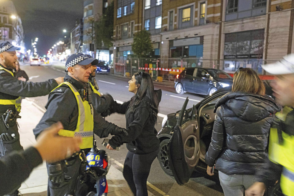 Two women are asked to leave the area after stopping to clash with protesters outside Kilburn Islamic Centre in London, Sunday, Sept. 25, 2022. The protesters were demonstrating against the death of Iranian Mahsa Amini, a 22-year-old woman, who died in Iran while in police custody, was arrested by Iran's morality police for allegedly violating its strictly-enforced dress code. (David Parry/PA via AP)