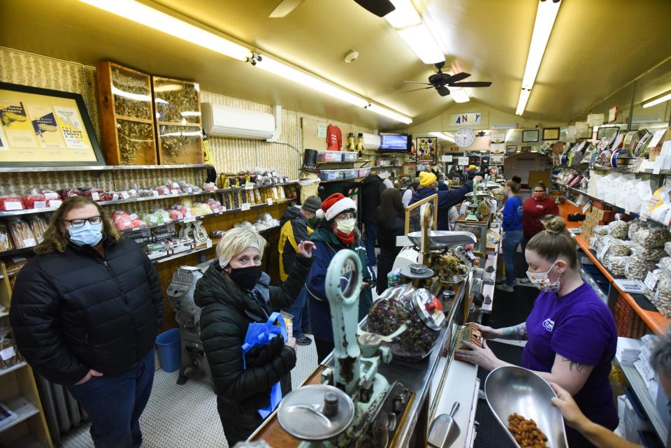 Customers purchase candy and nuts at the Peanut Shop prior to the Silver Bells Electric Light Parade in downtown Lansing, Friday, Nov. 19, 2021.
