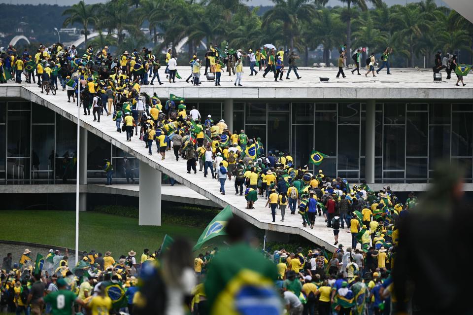 Hundreds of people in yellow and green shirts stand on and around a large building and connected ramp.