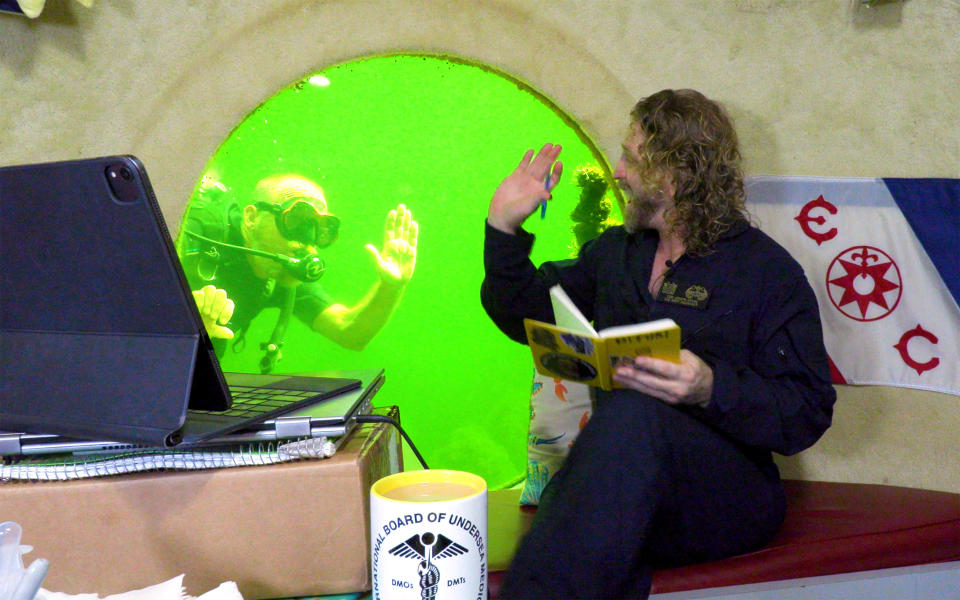 Diving explorer and medical researcher Dr. Joseph Dituri waves to scuba diver Thane Milhoan inside the Jules' Undersea Lodge, in a Key Largo lagoon, Florida Keys, Florida, U.S., May 13, 2023.  / Credit: Frazier Nivens/Florida Keys News Bureau/Handout via REUTERS