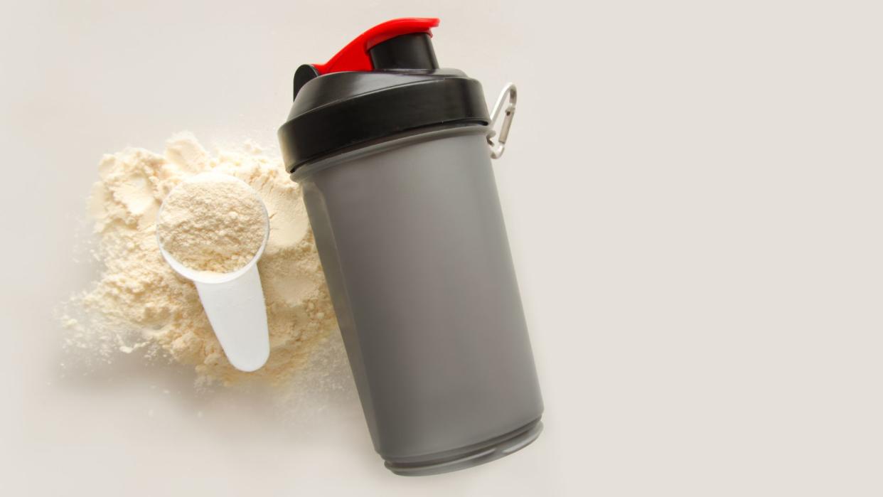  Protein powdet shaker with a scoop of protein next to it. 