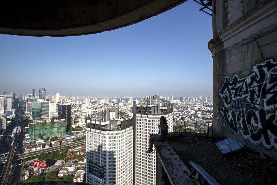 A visitor sits on a balcony of an abandoned building in Bangkok