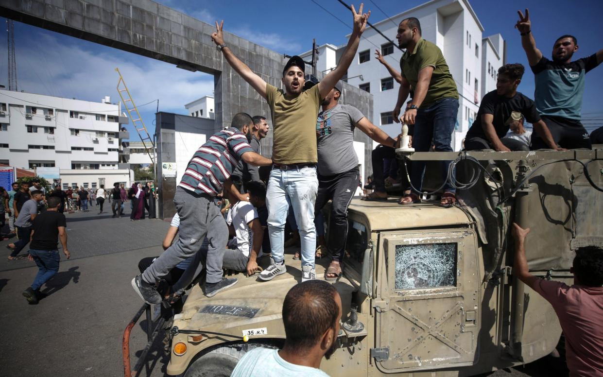 Palestinians ride an Israeli military jeep in the streets of Gaza
