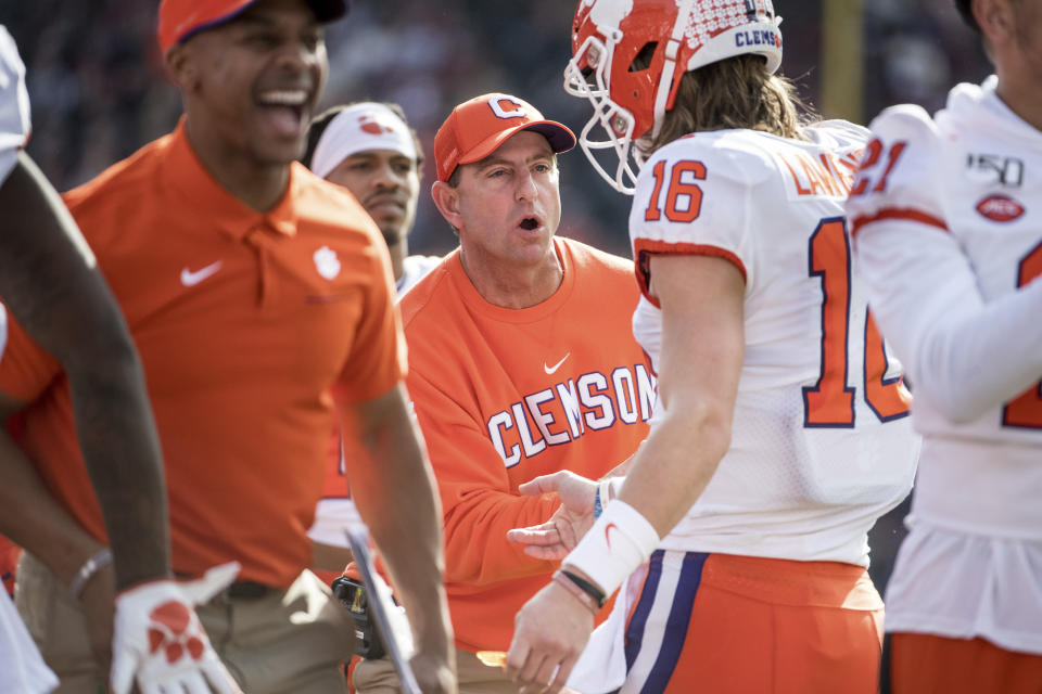 Clemson head coach Dabo Swinney greets Trevor Lawrence (16) after a touchdown against South Carolina during the first half of an NCAA college football game Saturday, Nov. 30, 2019, in Columbia, S.C. (AP Photo/Sean Rayford)