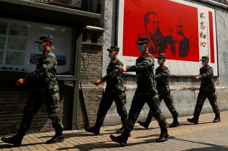 Chinese servicemen walk past portraits of German philosophers Karl Marx and Friedrich Engels and patrol a street near the Great Hall of the People on the opening day of the National People's Congress (NPC)in Beijing