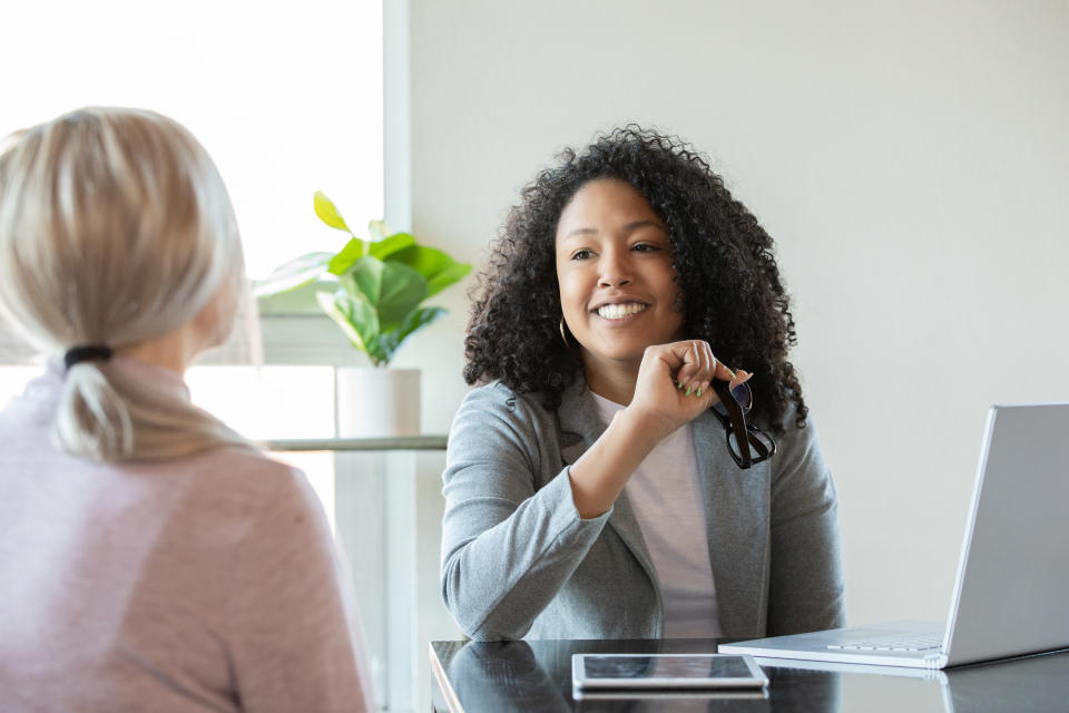 A woman with a blazer talking to another person at a table