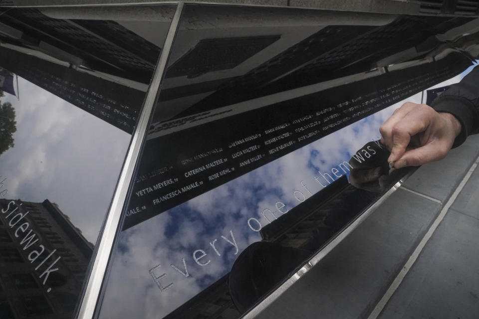 Contract detailer Giorgi Kvlividze makes final refinements to the Triangle Shirtwaist Memorial, a day before its official ceremonial opening, Tuesday Oct. 10, 2023, in New York. The memorial, featuring names engraved in a steel overhang that reflects below into mirroring panels, is being dedicated Wednesday at the Manhattan building where 146 people, mostly immigrant girls and women, were killed in a 1911 clothing factory fire. (AP Photo/Bebeto Matthews)