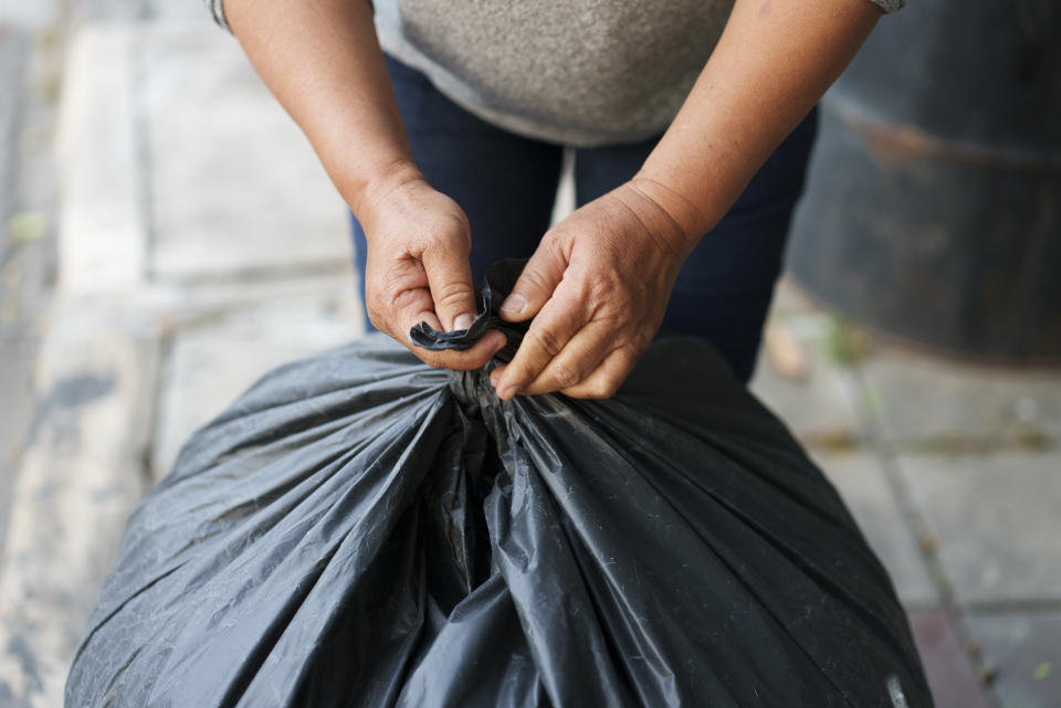 Someone tying up a bag of garbage