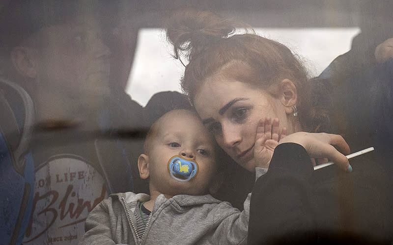 A woman holds her baby inside a bus as they leave Kyiv, Ukraine, on Feb. 24. Russia launched a wide-ranging attack on Ukraine on Thursday, hitting cities and bases with airstrikes or shelling, as civilians piled into trains and cars to flee. <em>Associated Press/Emilio Morenatti</em>