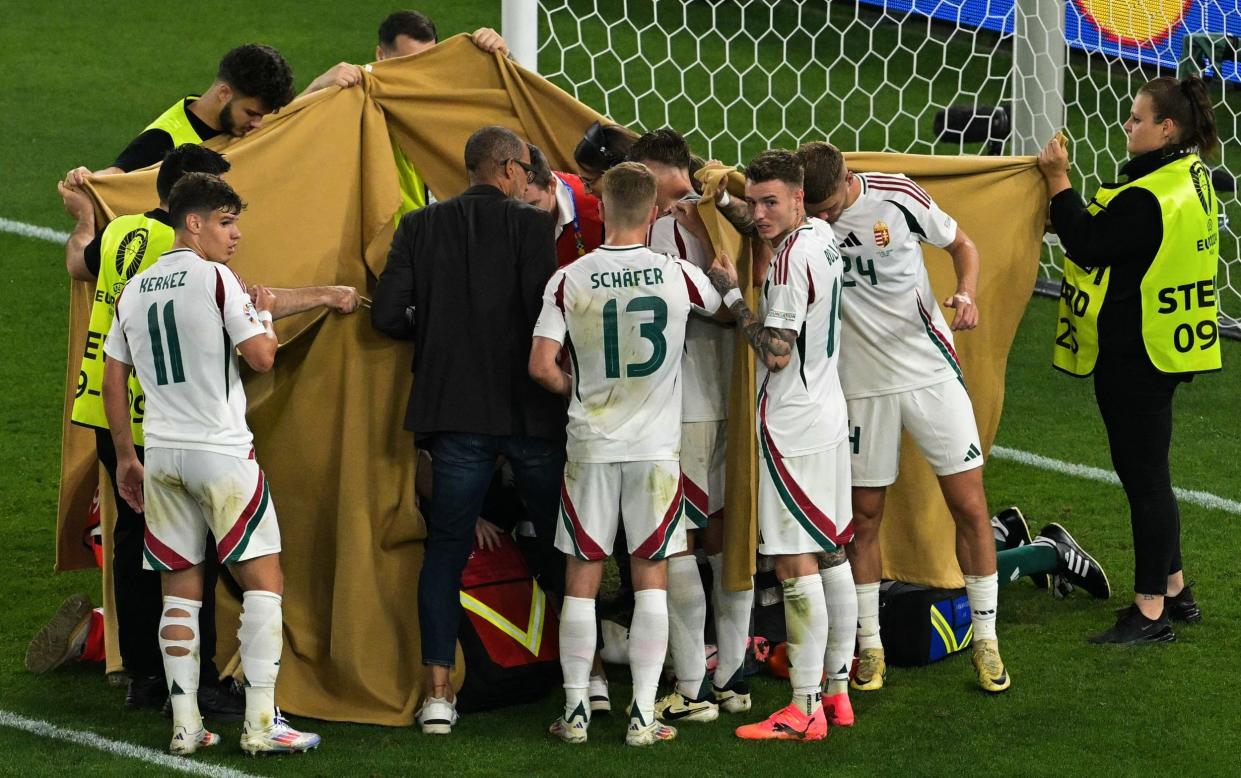 Players and stewards hold a cloth to hide Hungary's forward #19 Barnabas Varga receiving medical treatment during the UEFA Euro 2024 Group A football match between Scotland and Hungary at the Stuttgart Arena in Stuttgart on June 23, 2024