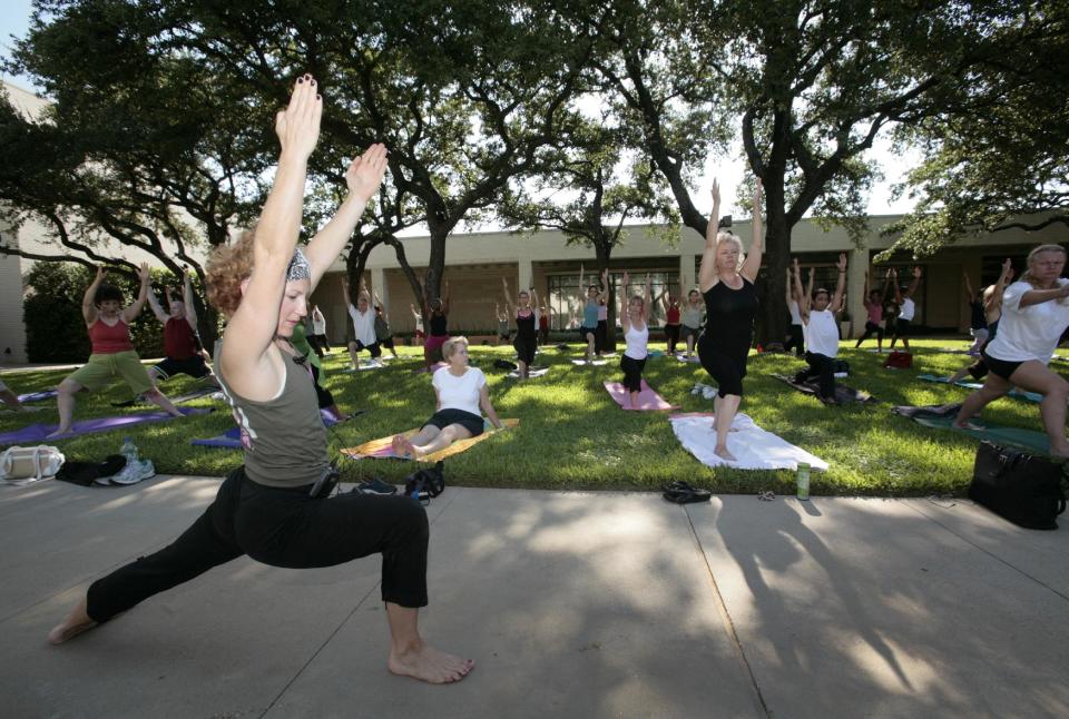 In this Aug. 8, 2009 file photo, Donna Fisher, foreground left, instructs a yoga class at North Park Center mall in Dallas. Dallas is a city that likes to do things big, but that doesn’t mean you’ll have to sell the ranch to have a good time here. (AP Photo/Tony Gutierrez)
