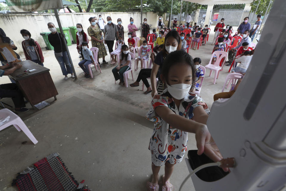 A young girl disinfects her hands before receiving a shot of the Sinovac's COVID-19 vaccine at a Samrong Krom health center outside Phnom Penh, Cambodia, Friday, Sept. 17, 2021. Prime Minister Hun Sen announced the start of a nationwide campaign to give COVID-19 vaccinations to children between the ages of 6 and 11 so they can return to school safely after a long absence due to measures taken against the spread of the coronavirus. (AP Photo/Heng Sinith)