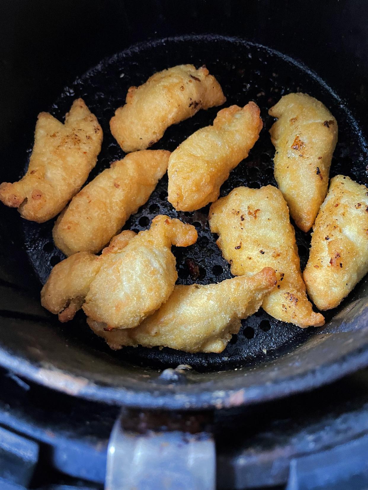 Stock photo showing an elevated view of inside an air fryer with a pile of golden brown, freshly cooked, battered chicken nuggets as part on Chinese meal. Healthier cooking concept.