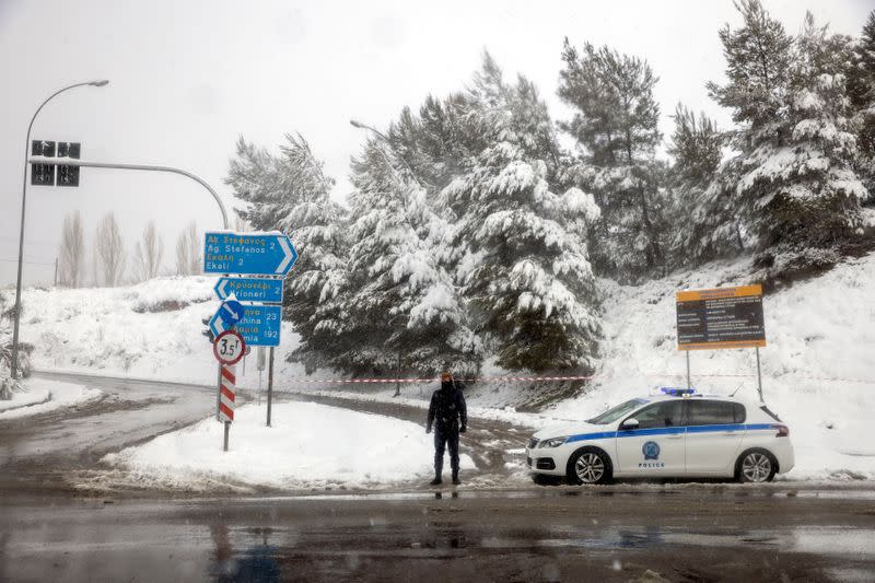 Un oficial de policía monta guardia en un punto de salida a la carretera nacional, que está cerrada debido a las fuertes nevadas, cerca del pueblo de Krioneri, Grecia, el 15 de febrero de 2021.