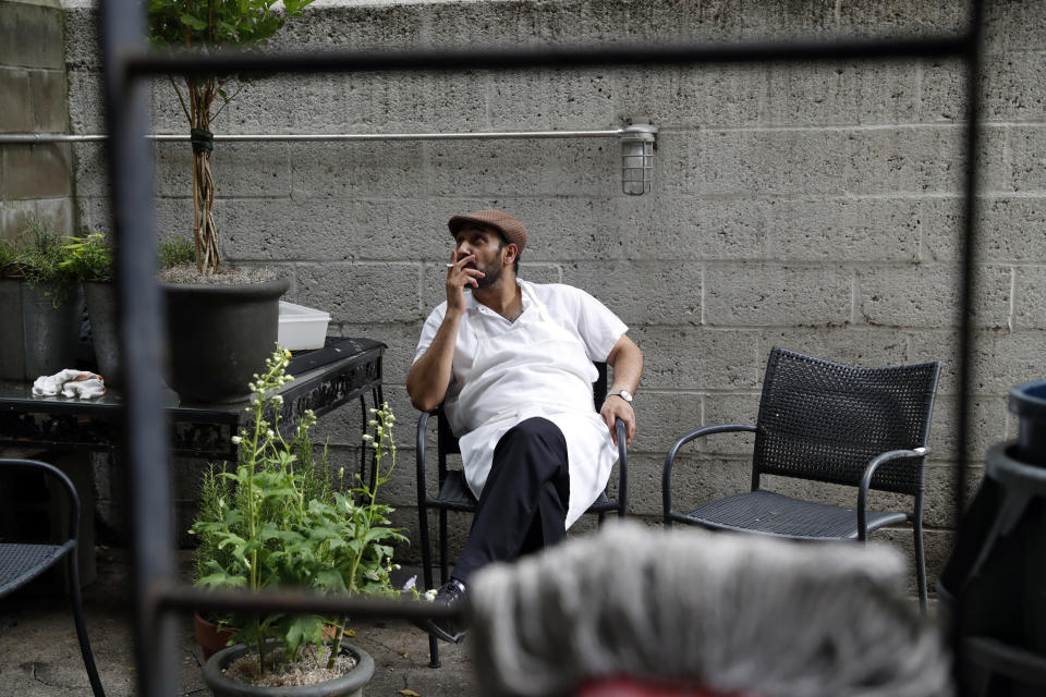 In this June 17, 2019, photo, refugee chef Diaa Alhanoun takes a break while preparing a special meal for the Refugee Food Festival held at Porsena, an East Village Italian restaurant that has hosted Alhanoun and his Mediterranean specialties for two consecutive years, in New York. The citizen-led festival is held in major cities across the globe each summer to promote refugee chefs and refugee causes. During the event, participating restaurants open their kitchens to chefs like Alhanoun to introduce food from the chefs' home countries to residents of their adopted country. (AP Photo/Kathy Willens)