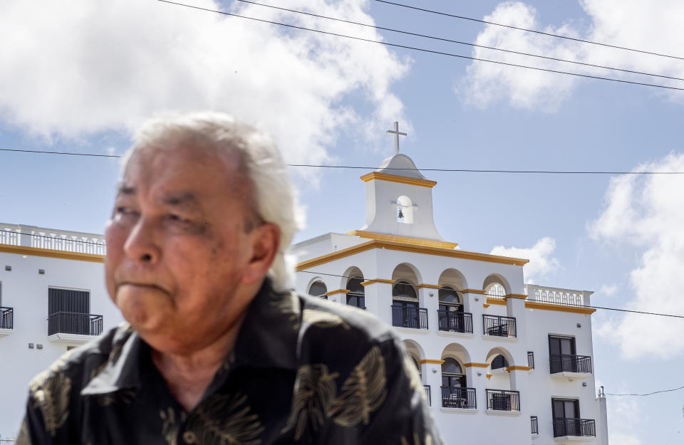 Leo Tudela recalls his allegations of sexual abuse at age 13 by a monk at the Saint Fidelis Friary, seen in the background, in Hagatna, Guam, Thursday, May 9, 2019. Tudela was eventually moved to live in the rectory of another church where Father Louis Brouillard took interest in him. That began an eight-month period during which Tudela alleges he was regularly raped and molested. "We're all human beings so there is always forgiveness but this person I don't think God will forgive him," he said. Brother Mariano Laniyo and Brouillard are now dead. Brouillard acknowledged abuse allegations before he died. (AP Photo/David Goldman)