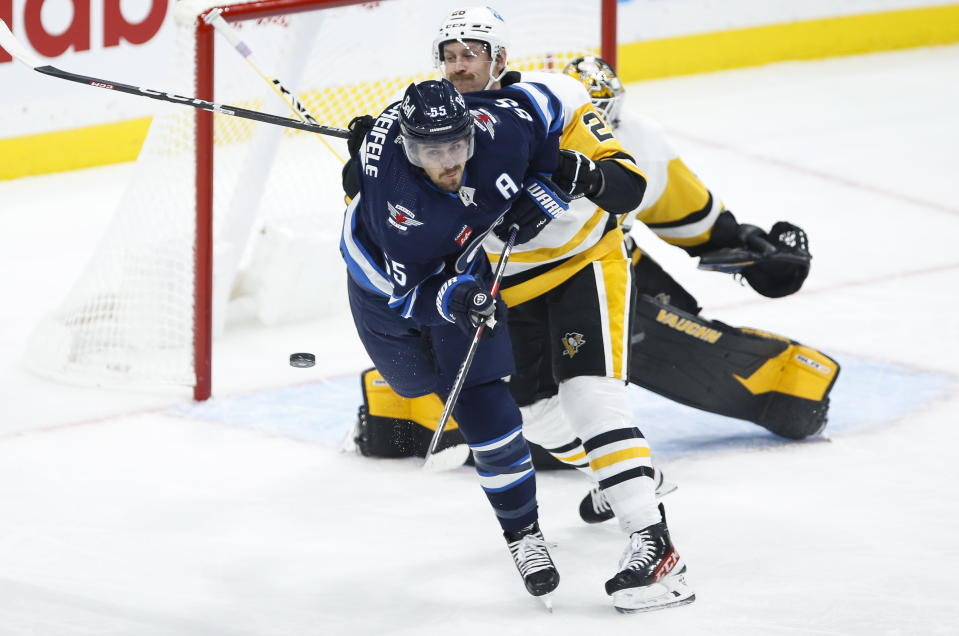 Winnipeg Jets' Mark Scheifele (55) avoids a shot from the point as Pittsburgh Penguins' Jeff Petry (26) defends in front of Penguins goaltender Tristan Jarry, back, during first-period NHL hockey game action in Winnipeg, Manitoba, Saturday, Nov. 19, 2022. (John Woods/The Canadian Press via AP)