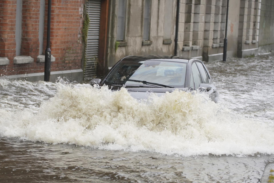 A car drives through flood water on Canal Quay in Newry Town, Co Down, which has been swamped by floodwater as the city's canal burst its banks amid heavy rainfall, Wednesday Nov. 1, 2023. Dozens of businesses were engulfed in the floods, with widespread damage caused to buildings, furnishings and stock. (Brian Lawless/PA via AP)