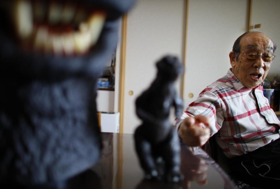 In this Monday, April 28, 2014 photo, original Godzilla suit actor Haruo Nakajima, who has played his role as the monster, points a figure of the monster he made for the movie, as he speaks during an interview at his home in Sagamihara, near Tokyo. Nakajima, 85, was a stunt actor in samurai films, when he was approached to take the Godzilla role. He had to invent the character from scratch, and went to the zoo to study the way elephants and bears moved. (AP Photo/Junji Kurokawa)