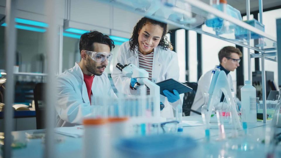 Workers use a microscope to do medical research in a modern laboratory.