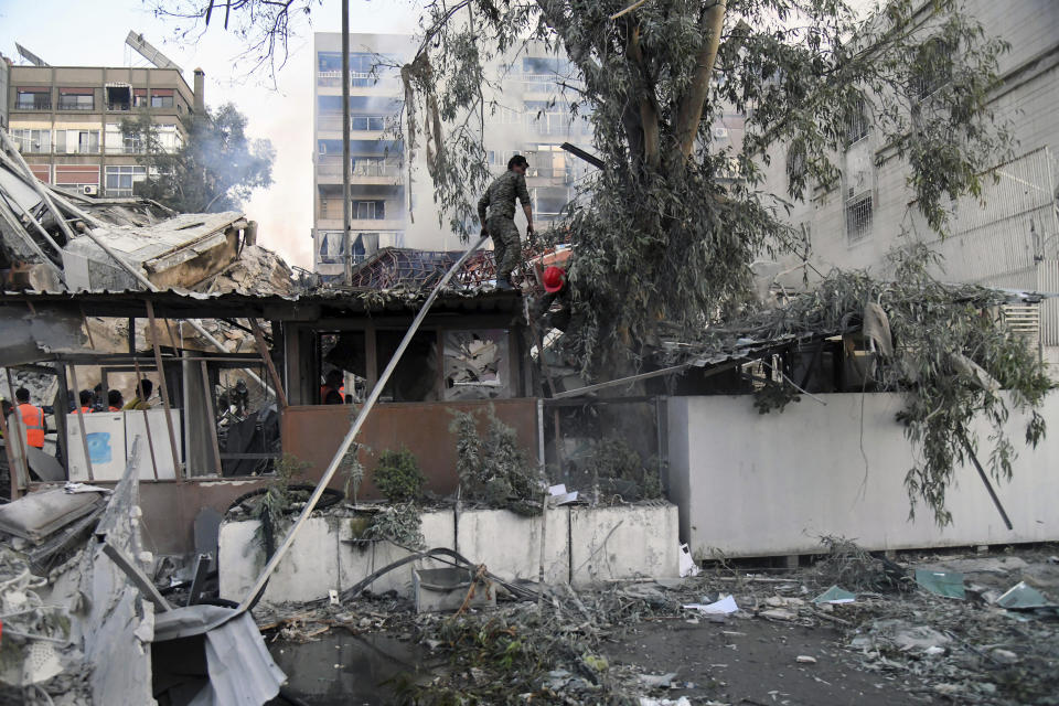 In this photo released by the official Syrian state news agency SANA, emergency service workers clear the rubble at a destroyed building struck by Israeli jets in Damascus, Syria, Monday, April 1, 2024. An Israeli airstrike has destroyed the consular section of Iran's embassy in Syria, killing a senior Iranian military adviser and roughly a handful of other people, Syrian state media said Monday. (SANA via AP)