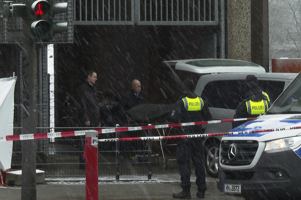 Morticians bring a covered stretcher to their vehicle at a building used by Jehovah's Witnesses in Hamburg, Germany Friday, March 10, 2023. Shots were fired inside the building on Thursday evening, with multiple people killed and wounded, police said. (Steven Hutchings/Tnn/dpa via AP)