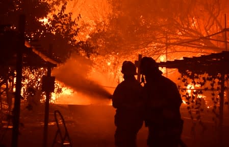 Firefighters battle a wind-driven wildfire called the Saddle Ridge fire in the early morning hours Friday in Porter Ranch