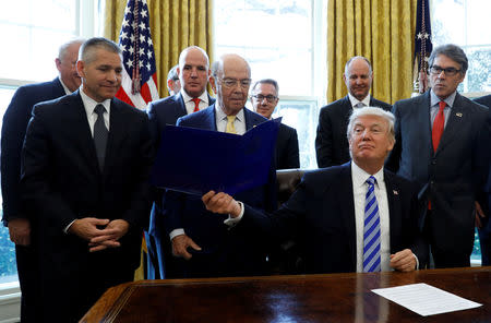 FILE PHOTO: U.S. President Donald Trump smiles after announcing a permit for TransCanada Corp's Keystone XL oil pipeline while TransCanada Chief Executive Officer Russell Girling (L), U.S. Commerce Secretary Wilbur Ross (C) and U.S. Energy Secretary Rick Perry (R) stand beside him in the Oval Office of the White House in Washington, U.S., March 24, 2017. REUTERS/Kevin Lamarque/File Photo