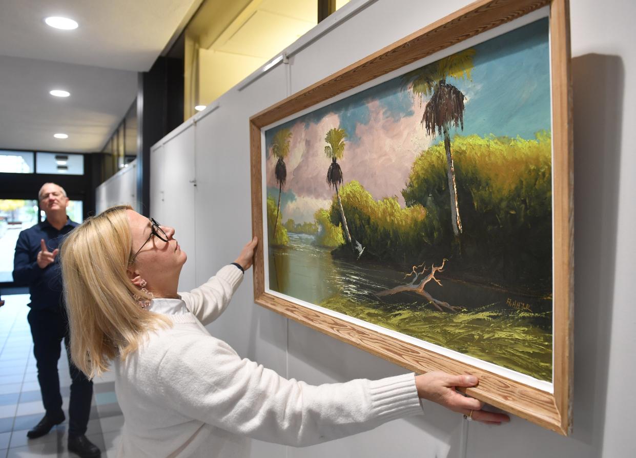 City of Sarasota Public Art Manager Mary Davis Wallace, straightens a painting by one of the original Florida Highwaymen, Albert Hair, as she helps prepare the exhibit in Sarasota City Hall atrium on Monday.