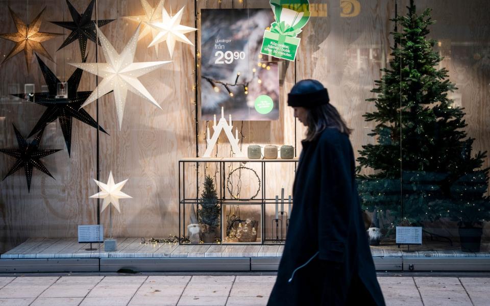 A woman passes a Christmas decorated shopping window in central Stockholm  - Shutterstock 