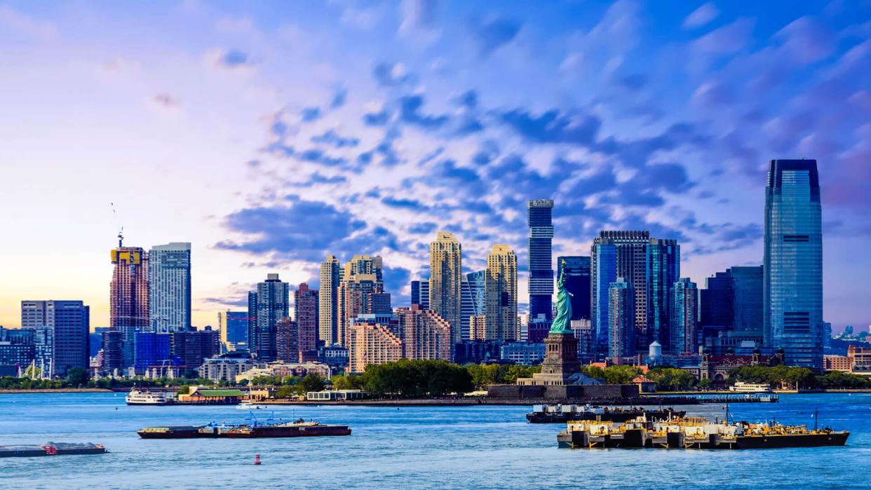 The skyline of Jersey City, New Jersey from New York Harbor with the Statue of Liberty in the foreground.